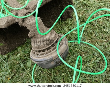 A drum of a brush cutter with an unwound long green vein on a background of mowed grass. A tool for cutting grass. Royalty-Free Stock Photo #2451350117