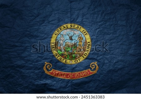 colorful big national flag of idaho state on a grunge old paper texture background