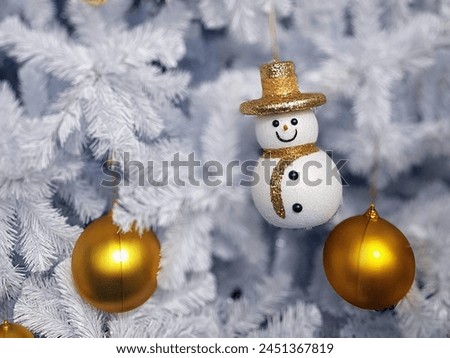 a photography of a snowman ornament hanging from a christmas tree.