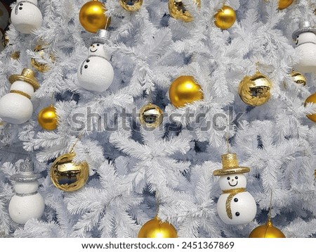 a photography of a white christmas tree with gold ornaments and snowmen.