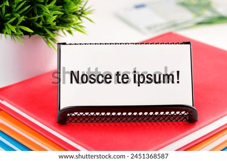 Latin proverb NOSCE TE IPSUM (know yourself) on white business cards in delivery on a light background