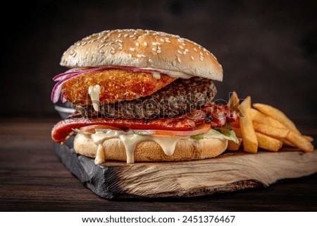 Burger with puffy beef patty, breaded cheese, iceberg lettuce. Juicy delicious hamburger on darkmood picture for restaurant decoration, poster. 