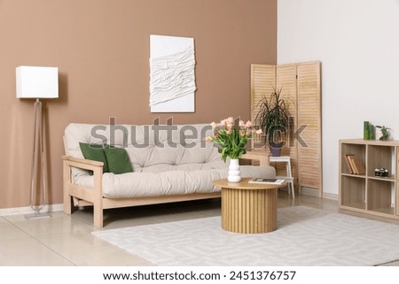 Interior of stylish living room with sofa, coffee table and tulips