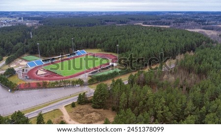 Soccer city stadium located in a pine forest, drone view. High quality photo aerial view from drone of a football stadium with a football field located in a pine forest
