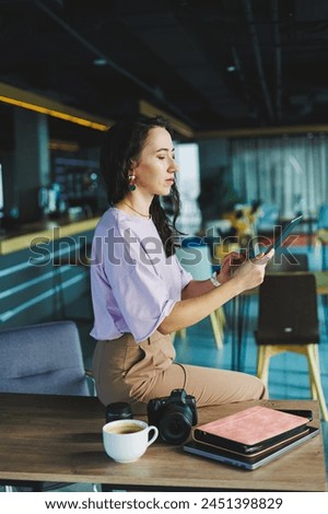 A female photographer works on a computer at her desk. A young woman uses a tablet to retouch an image.