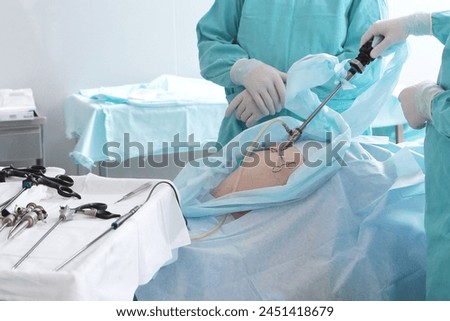 Surgery through small holes in abdominal cavity. Team of surgeons. Laparoscopic instruments in hands of surgeon. Modern surgery. Laparoscopic surgery. Royalty-Free Stock Photo #2451418679