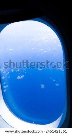 Captured from the bird's eye view of a plane, this photo reveals a solitary island nestled like a precious gem in the vast expanse of ocean. With its lush greenery kissing the shores and waves gently. Royalty-Free Stock Photo #2451421561