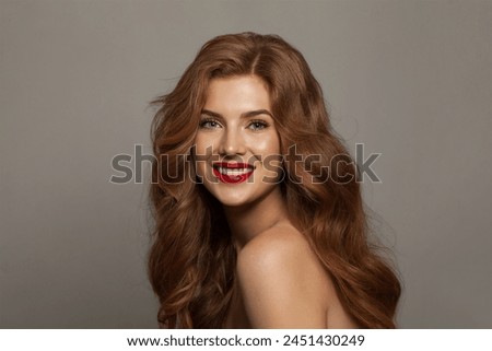 Joyful fashionable redhead woman with long wavy hair and make-up. Studio headshot portrait of fashion model lady with red colorful shine lipstick. Haircare, skin care and coloration concept