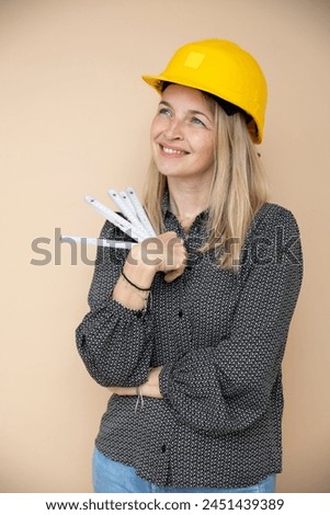 woman, architect, technician, builder, polisher with yellow safety hat and yellow folding rule in front of brown background Royalty-Free Stock Photo #2451439389