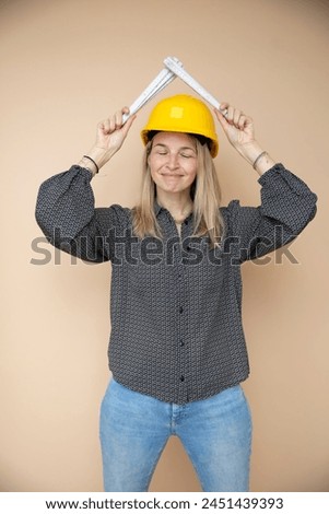 woman, architect, technician, builder, polisher with yellow safety hat and yellow folding rule in front of brown background Royalty-Free Stock Photo #2451439393