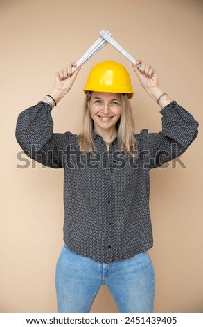 woman, architect, technician, builder, polisher with yellow safety hat and yellow folding rule in front of brown background Royalty-Free Stock Photo #2451439405