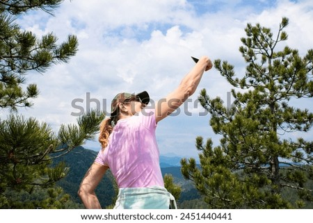Tourist girl taking selfie with smartphone while Hiking in nature at the top of the mountain