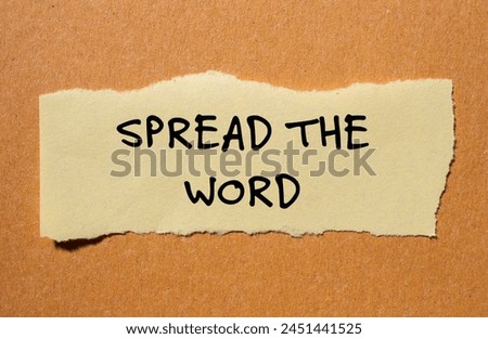 Spread the word written on ripped yellow paper piece with cardboard background. Conceptual spread the word symbol. Copy space.