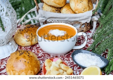 A bowl filled with hot soup sits atop a wooden table.