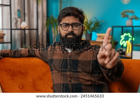Displeased upset Indian young man reacting to unpleasant awful idea, dissatisfied with bad quality wave hand shake finger No dismiss idea don't like proposal. Arabian guy sitting at home room couch Royalty-Free Stock Photo #2451465633