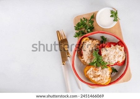 Stuffed bell peppers on white kitchen table background. Colorful red, yellow, green peppers with diet chicken minced meat, vegetables and rice, with white sauce, Balanced healthy food recipe