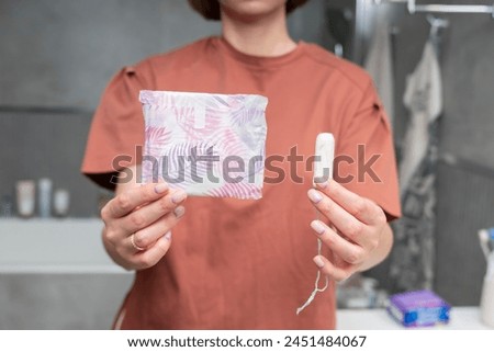 In a thoughtful moment, a woman contemplates her choice between pads and tampons, considering the comfort and convenience of each option Royalty-Free Stock Photo #2451484067