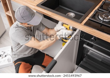 Caucasian Professional Cabinetmaker in His 40s Assembling Kitchen Cabinets Furniture Royalty-Free Stock Photo #2451493967