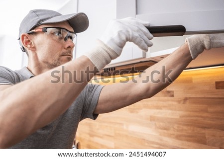 Cabinetmaker Assembling Kitchen Cabinets. Modern Clean White Furniture Royalty-Free Stock Photo #2451494007