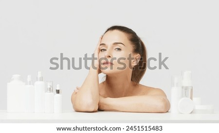 Gorgeous middle aged woman touching her perfect skin. Beautiful portrait of a 40-50 year old woman advertising anti-aging facial products, salon care, skin tightening, isolated on white background. Royalty-Free Stock Photo #2451515483
