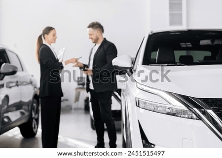 An interested buyer consults with a car dealership manager about the models and characteristics of a modern electric car. Concept of buying and selling a car, deal.