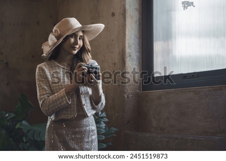 Beautiful young Asian woman brunette woman wearing fashion clothes casual dress and camera. Portrait fashion model in beige clothes at traditional architecture old wall vintage building. Retro style.