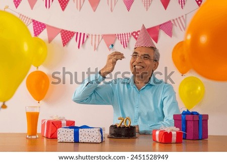 Happy senior man blowing party horn on his 70th birthday