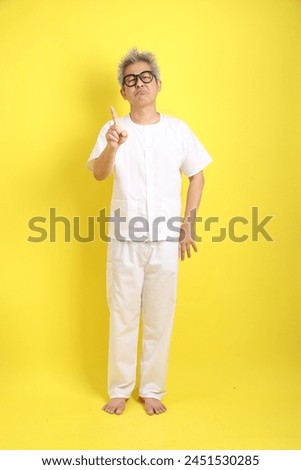 Chinese Vegetarian Festival. Senior man wearing white clothing with gesture of stop, forbid, refusing, No isolated on yellow background. Nine emperor god, J festival.
