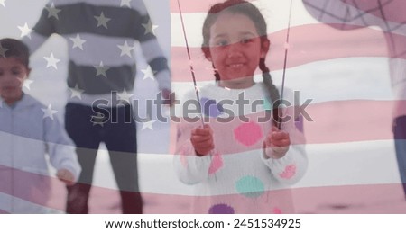 Image of flag of united states of america over biracial girl holding sparklers. American patriotism, diversity and tradition concept digitally generated image.