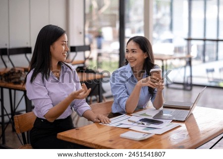 Two engaging Asian businesswomen having a lively discussion during a coffee break in a casual office setting.

 Royalty-Free Stock Photo #2451541807