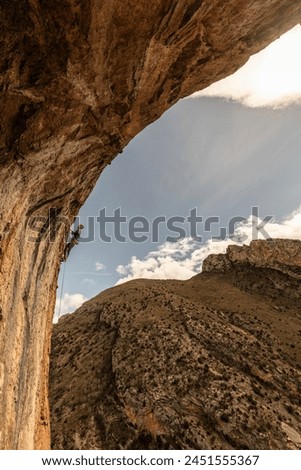 A person is climbing a rock wall with a view of the mountains in the background. Concept of adventure and excitement as the climber navigates the challenging terrain