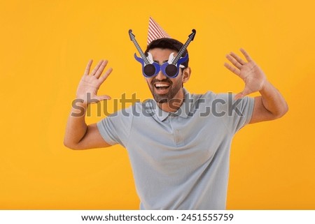 Funny young man wearing guitar shaped eye glasses with party hat
