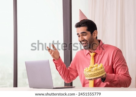 Happy corporate man celebrating birthday through video call chatting with friends in office