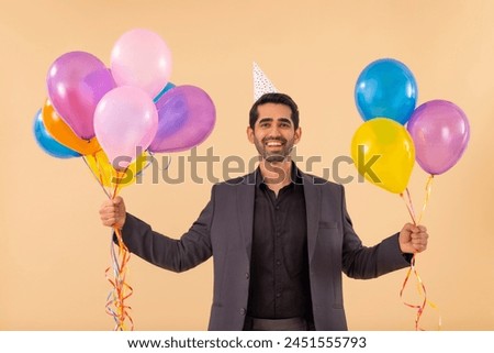 Happy business man in party hat holding balloons in hands