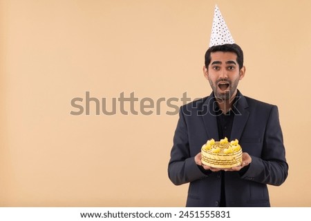 Portrait of a happy businessman wearing a party hat with a birthday cake in his hand