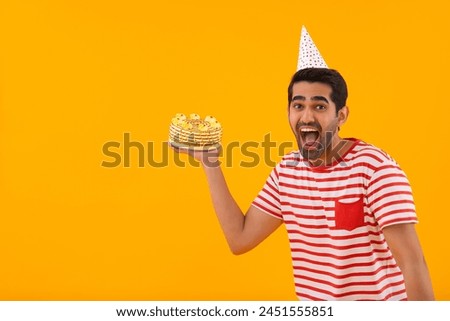 Happy young man posing in front of camera with birthday cake in hand