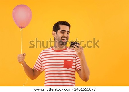 Portrait of happy young man holding balloon in hand and eating a piece of cake
