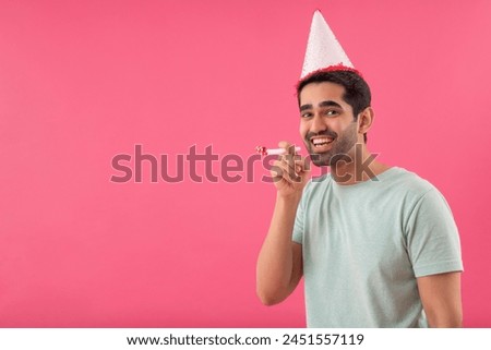Happy young man wearing party hat and holding party horn in hand
