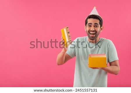 Excited young man wearing party hat and opening surprise gift box