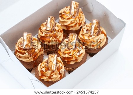 Peanut butter cupcakes with vanilla cream cheese frosting and salted caramel on top, png. Beautiful box with dessert