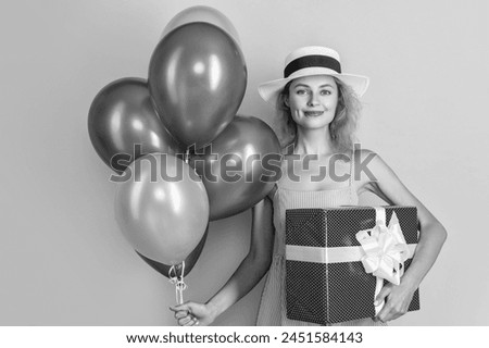 cheerful birthday woman with present and balloons. birthday woman with present isolated on yellow. birthday woman with present in studio. birthday woman with present on background