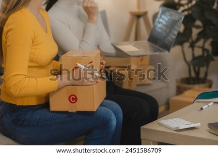 Two business owners are checking customer information on a package before it is delivered to the buyer, Two co-workers are checking that order data matches sales figures. Royalty-Free Stock Photo #2451586709