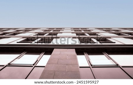 Upward view of a building showcasing geometric window patterns and the contrast of its structured facade