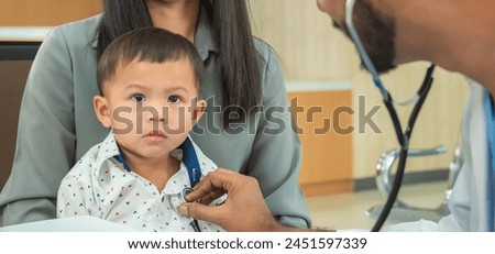 Banner of pediatrician hold stethoscope exam child boy patient with mother, black pediatrician seduce by toy kid pediatric checkup in hospital children medical care Royalty-Free Stock Photo #2451597339