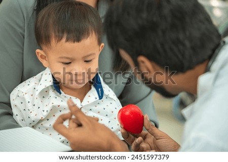 pediatrician hold stethoscope exam child boy patient with mother, black pediatrician seduce by toy kid pediatric checkup in hospital children medical care Royalty-Free Stock Photo #2451597379