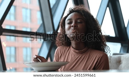Such delicious tasty filling food. Close-up of a curly-haired beautiful woman tasting food in a new restaurant.
