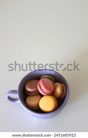 Purple cup filled with pastel macarons on white background. Selective focus.