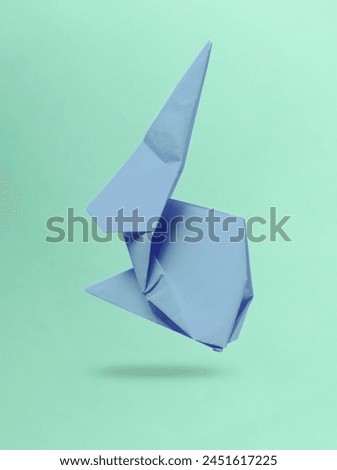 Purple origami rabbit levitating on blue background