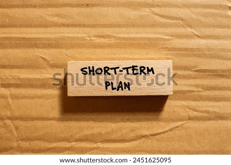 Short term plan words written on wooden block with cardboard background. Conceptual short term plan symbol. Copy space. Royalty-Free Stock Photo #2451625095