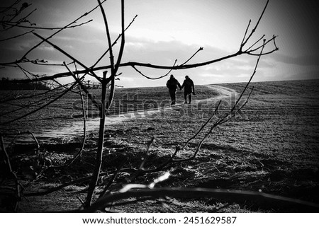 Two in love people on a walk in the countryside, walk through the field and heaven with clouds, outdoor, black and white photo